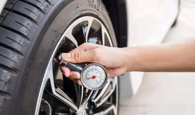 Hand measuring car tire pressure with a digital gauge