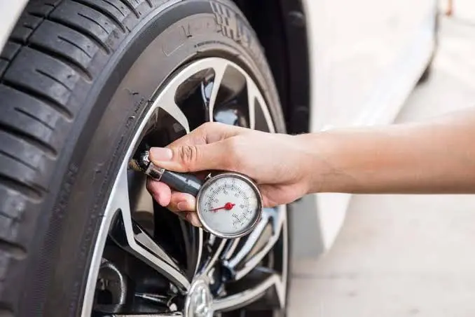 Hand measuring car tire pressure with a digital gauge